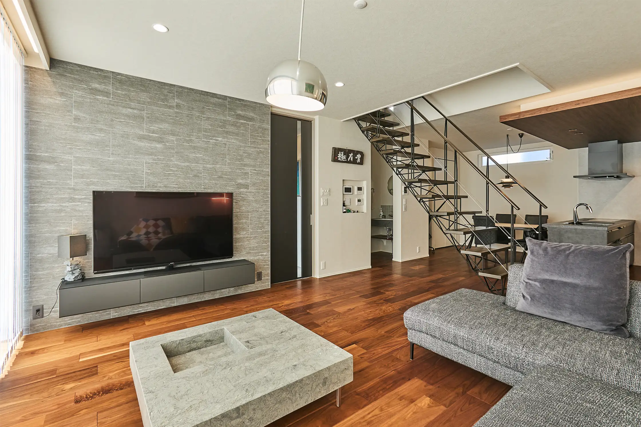 吹き抜け階段とシックなインテリアが調和したモダンなリビング空間