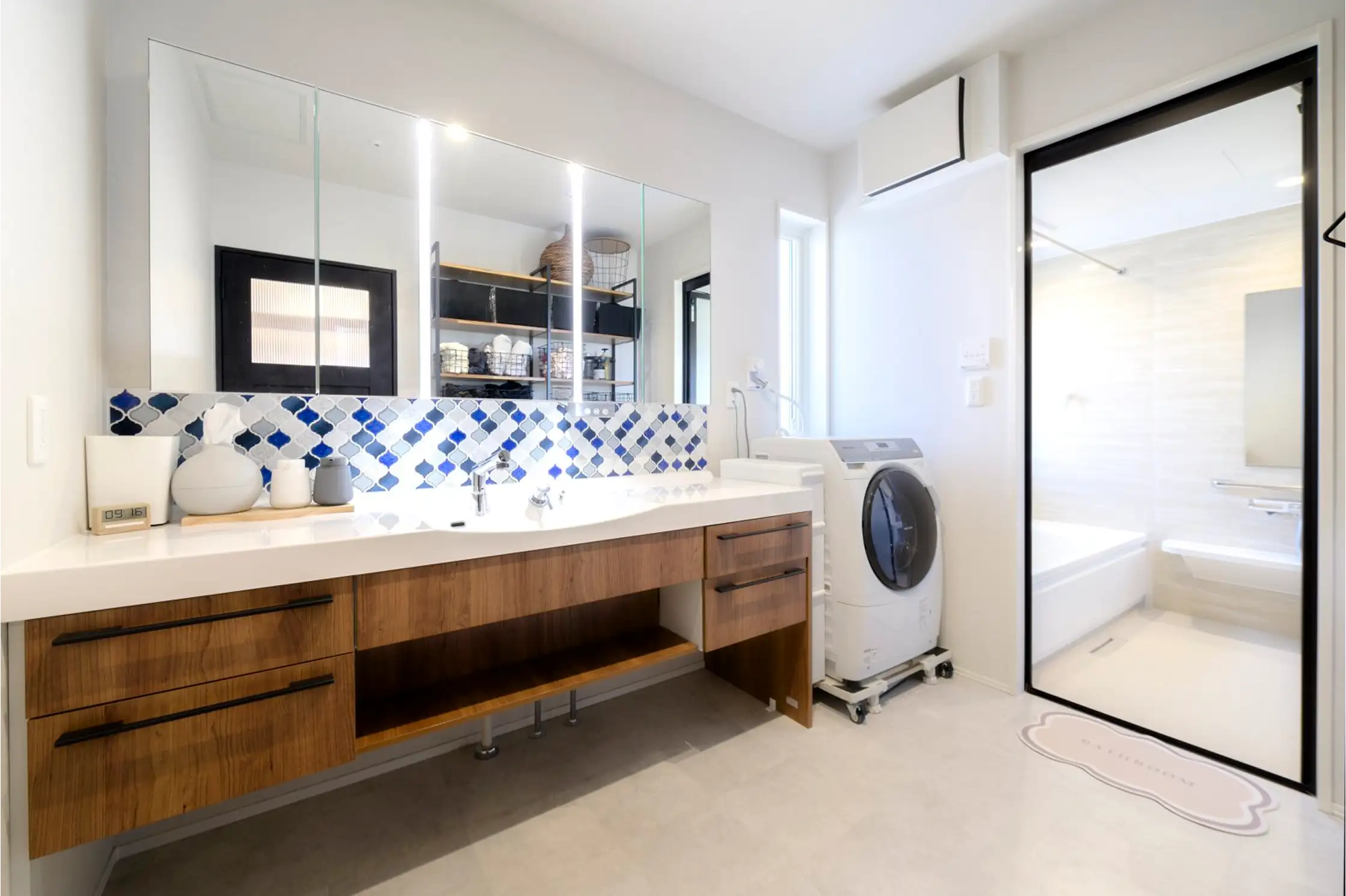 壁の幅を大きく使った鏡とその下のタイルが印象的な洗面脱衣室