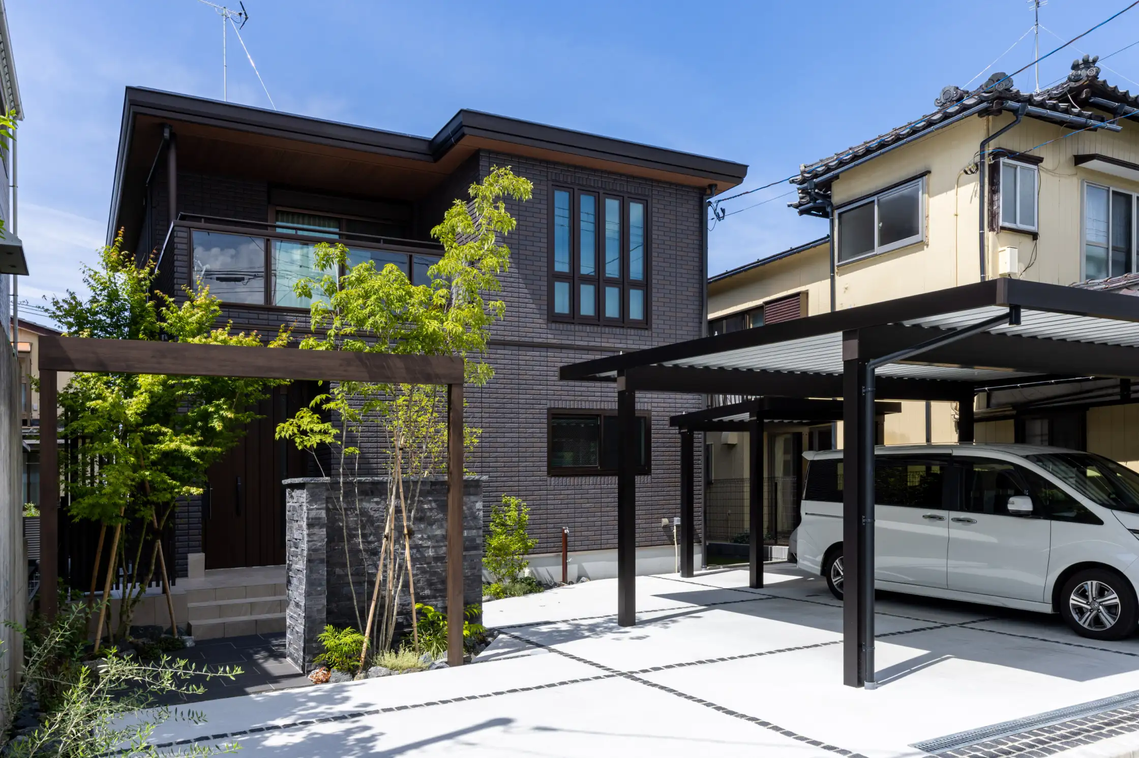 スタイリッシュなアーチがあるアプローチとカーポートと植栽がある外観