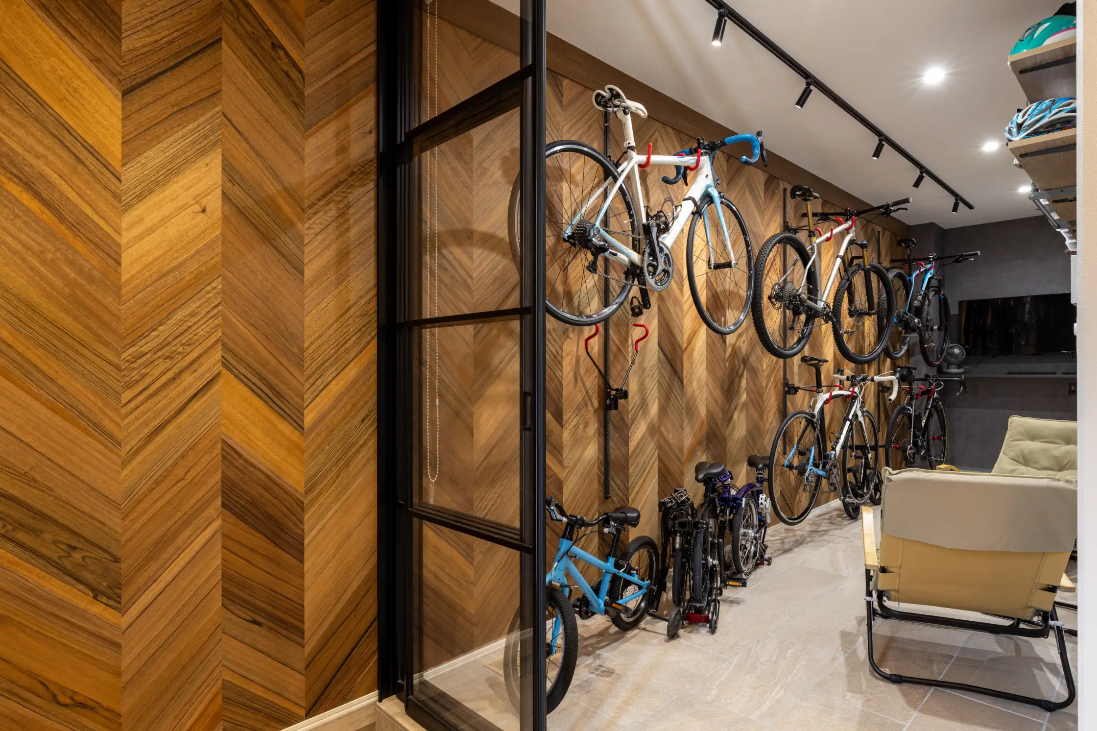 ヘリンボーンの壁にディスプレイされた家族の自転車とアウトドアチェア