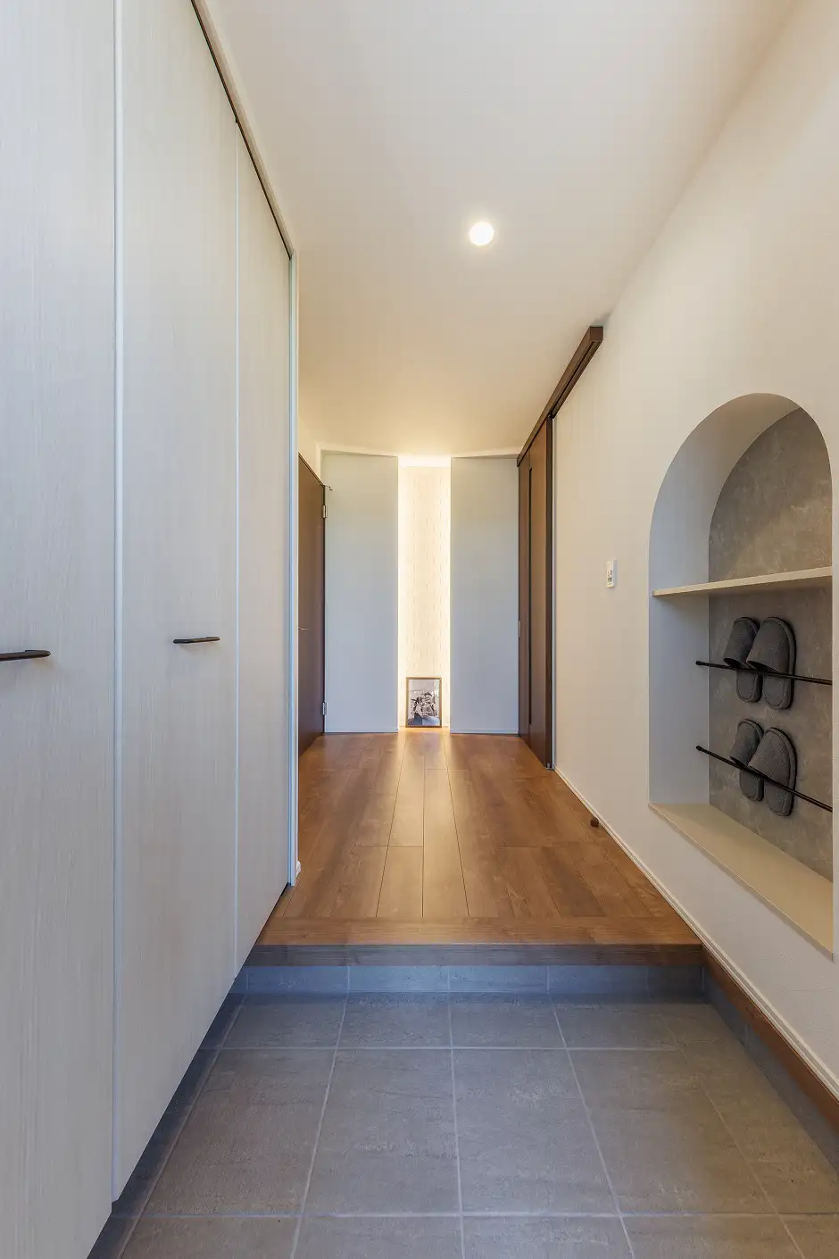 間接照明付きのアクセントウォールとニッチ収納が備わったゆとりのある玄関