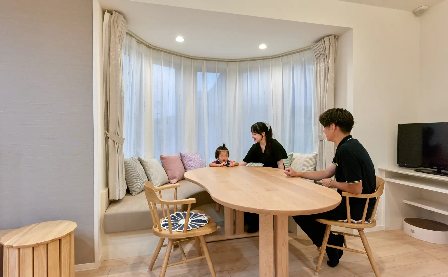 ボウウインドウのあるダイニングスペースで、ご夫婦とお子様が団らんしている様子