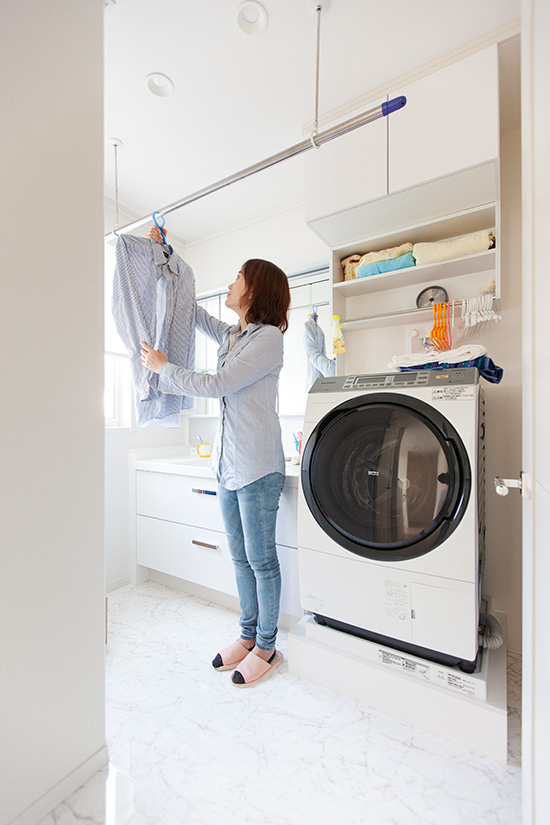 ランドリールームで洗濯物を干す妻