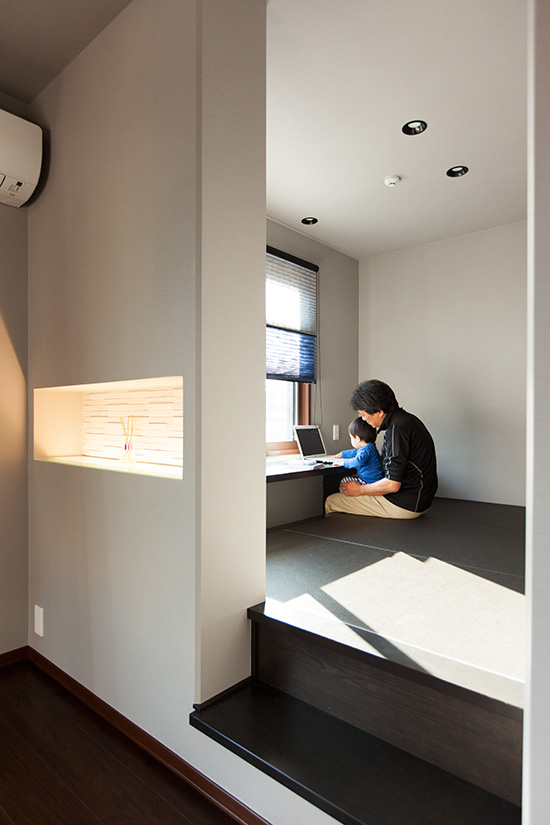 書斎で父親の膝に座り一緒にパソコンを見る子ども