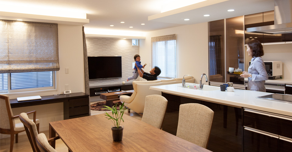 リビングで子どもをあやす夫とキッチンから見守る妻