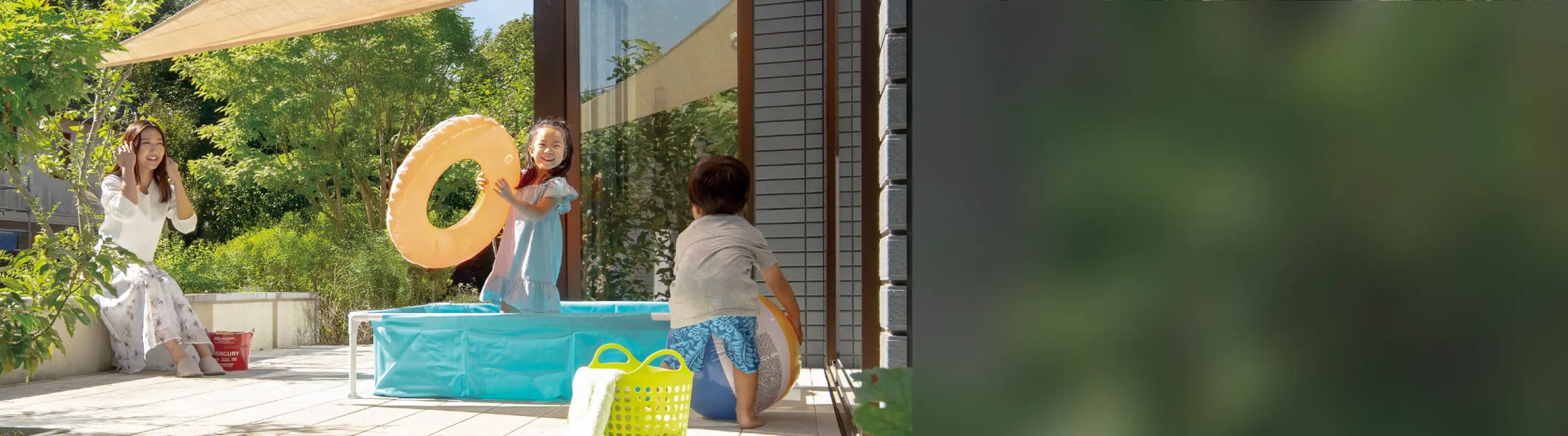 テラスで水遊びをする子供たちと見守る母親