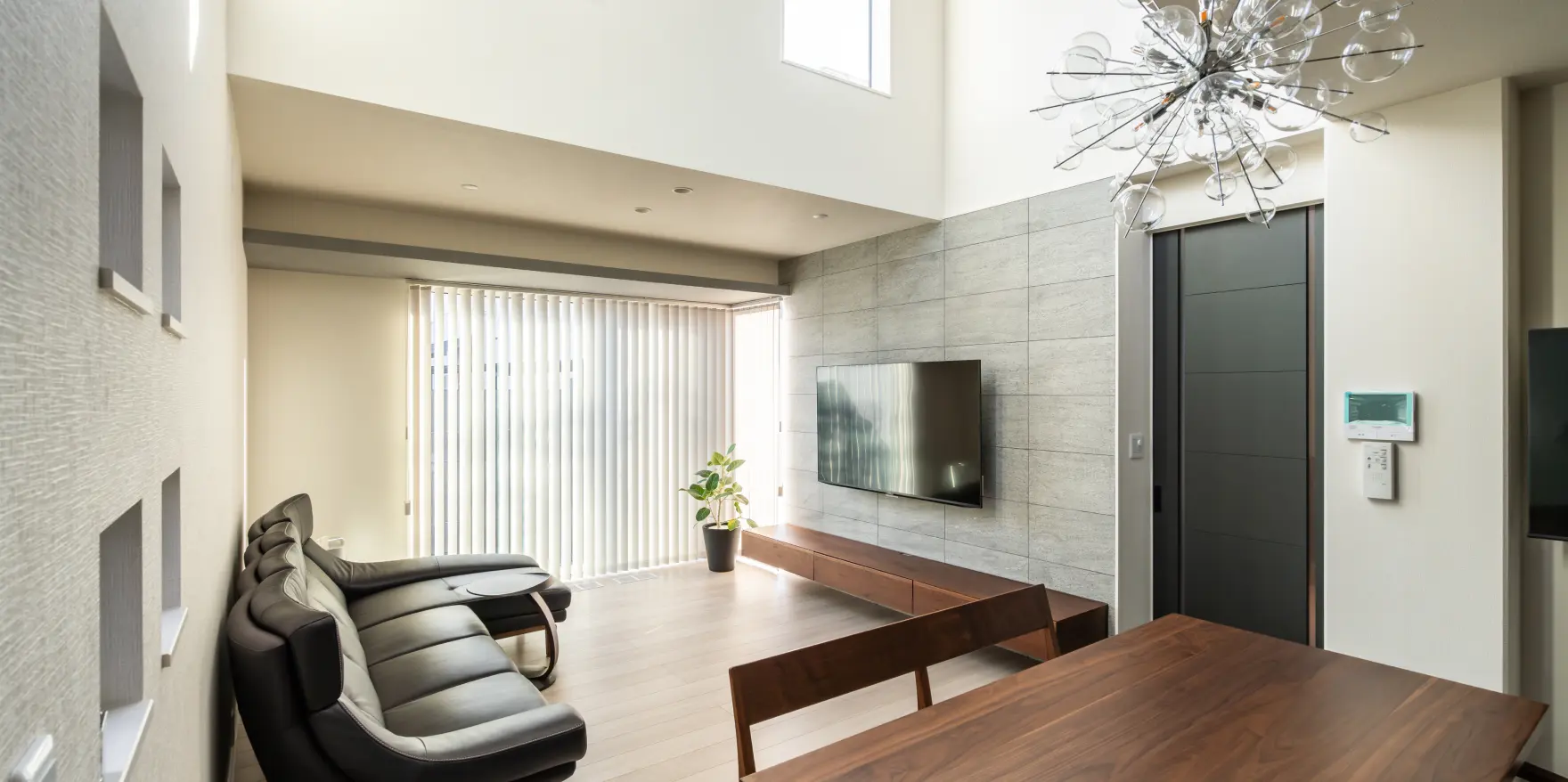 吹き抜けから光が降り注ぐ落ち着いた印象のリビングルーム