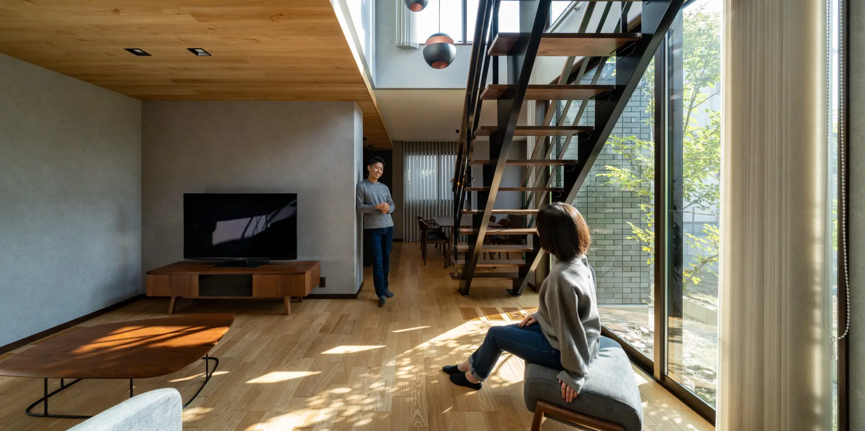 光が差し込む明るいリビング階段の下で会話する夫婦