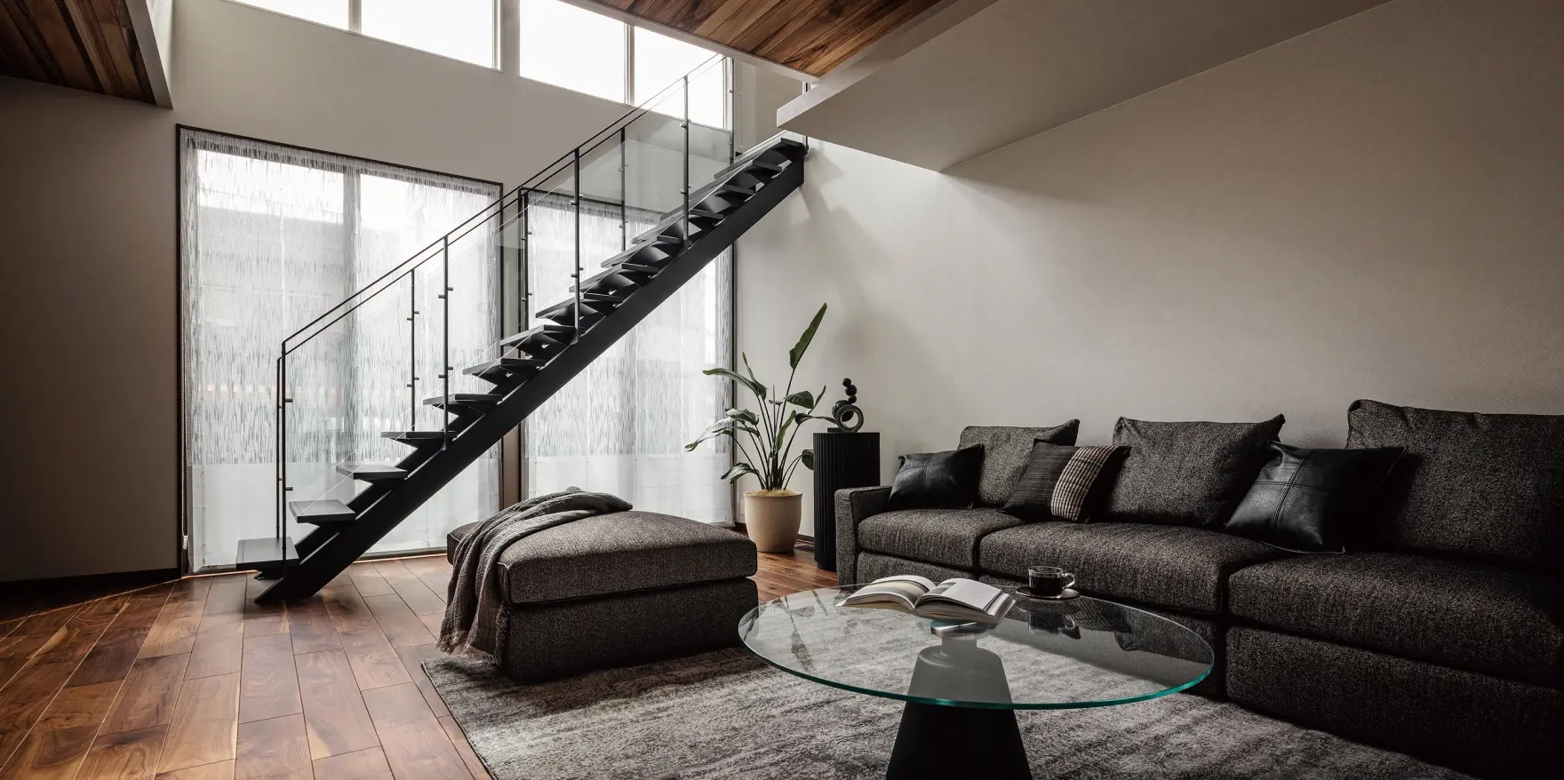 グレートーンの階段が設けられた吹抜けのある落ち着いた印象のリビング