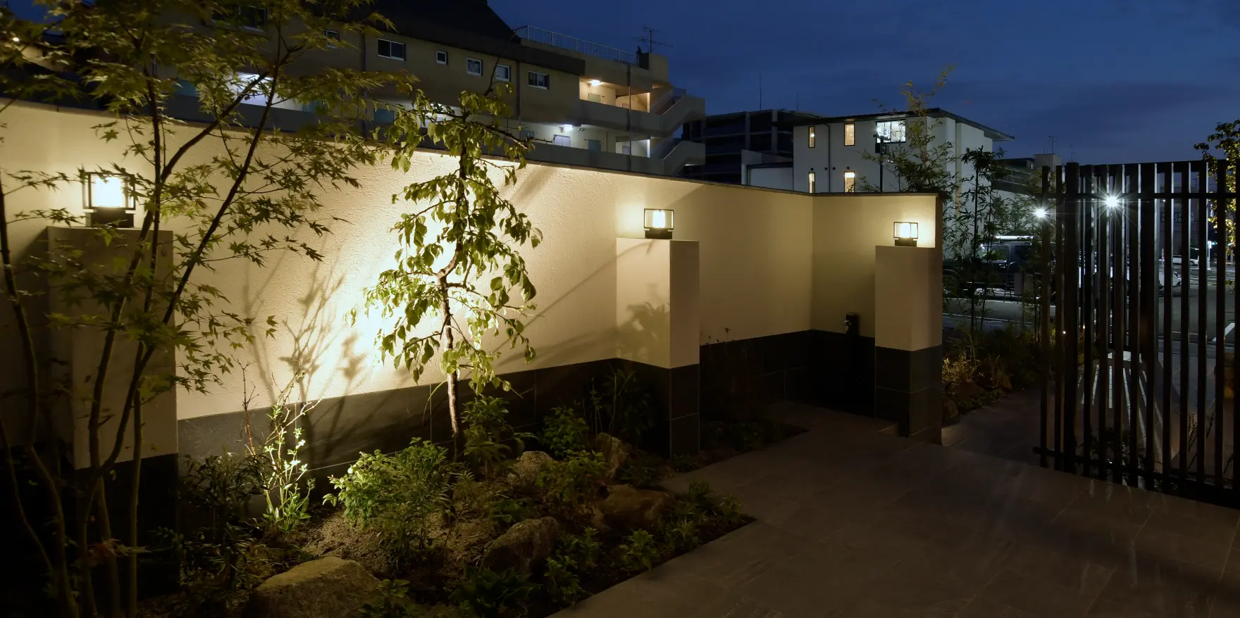 夜間にライトアップされた塀と植栽の陰影が際立つ幻想的な外構