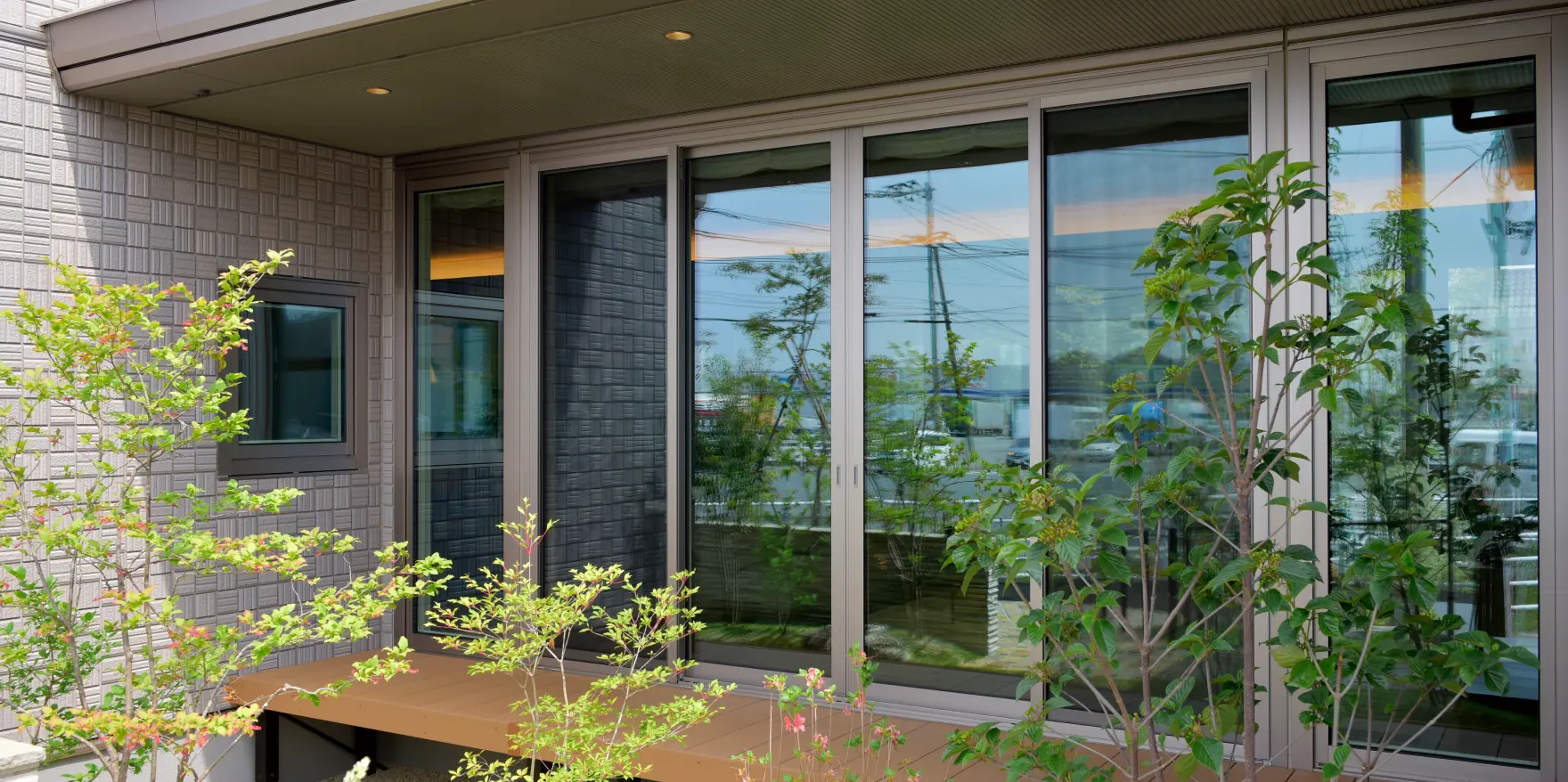 大きな窓に映し出された庭の緑が印象的な、ウッドデッキのあるテラス